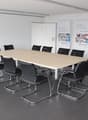 conference room with long table, black chairs, white walls, banners