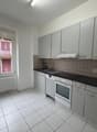 modern kitchen with white tiles, white cabinets, black countertops, white appliances, window with view to the outside