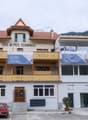 2 story building, brown roof, yellow balconies, white walls, parking lot in front