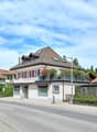 Swiss style houses, brown roofs, white walls, red shutters, balconies, green trees