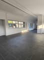 Empty room with white walls, gray tiled floor, large windows, and two white doors