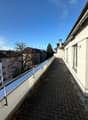 View of a roof terrace with paved floor, metal railings, and a clear view of the skyline.
