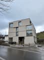 modern three story building, concrete, glass windows, raised ground floor, multiple balconies