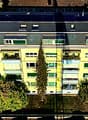 5 story yellow building, multiple balconies, many windows, solar panels