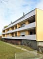 3 story apartment building, yellow and white, balconies, garage