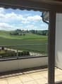 sliding glass door, balcony, metal railing, tiled floor, view of a green field