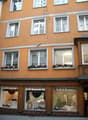 orange building, windows with white frames, holiday decorations on the windows, storefronts with window displays