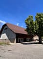 Warehouse with brown roof, concrete base, parking lot in front, trees on both sides
