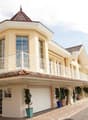 2 story house, yellow exterior, multiple windows, balcony, garage, paved road