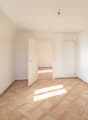 Empty room with wooden parquet flooring, white walls, two windows, and an open door leading to another room.