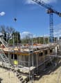 House under construction, scaffolding, crane, workers, yellow van, trees, houses, street light