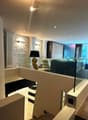 Spacious living room with modern decor, including a fireplace, arched windows, and a large sofa. The room has a mix of contemporary and traditional elements, with a stone accent wall and recessed lighting.