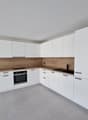 modern white kitchen with wooden countertops, white cabinets, grey tiled floor, gas stove, oven, and integrated appliances