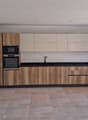 modern kitchen with wooden cabinets, tiled flooring, microwave, oven, sink, and a glass door