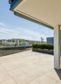 Tiled balcony, large glass doors, metal railings, large bushes, open view, high contrast shadows