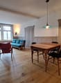 wooden floor, wooden table, blue sofa, red chair, wooden cabinet, lamp, tripod