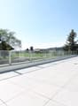 large balcony with glass railings, tiled floor, view of the surrounding landscape