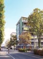 A modern apartment building with multiple balconies, surrounded by trees and greenery.