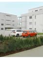 Two story white residential buildings, several parked cars, bushes