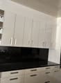 White cabinets, black countertops, gas stove, built-in oven, pull-out shelves, drawers with silver handles, modern design
