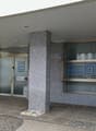 Office building, glass entrance, gray facade, security cameras, signage