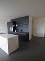 modern kitchen with marble countertop, black cabinets, stainless steel appliances, white walls, gray flooring
