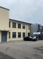 Two-story building, light yellow facade, blue double doors, windows, cars parked in front