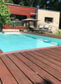 Swimming pool with wooden deck, lounge chairs, umbrellas, and plants