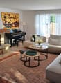 Fireplace, piano, two sofas, coffee tables, rug, paintings, lamp, plant
