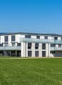modern white building, balconies, garden, wide field in front