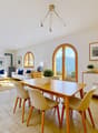 Dining room with a wooden table, white chairs, a white couch, a white cabinet, a wooden floor, and a chandelier
