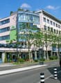 A multi-story building with a rooftop terrace, multiple windows, and a car parking area on the first floor.