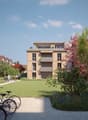 Modern apartment buildings with balconies, landscaped area with trees, a green lawn, and a paved pathway for bicycles
