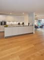 Open plan kitchen and living room, wooden floor, white cabinets, large windows, dining table, couch, TV