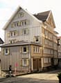 3 story building, wooden exterior, multiple windows, brown doors, cobblestone street