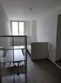 Minimalist bedroom with white walls, hardwood flooring, a metal shelving unit, and a bed frame. The room appears to be in a state of renovation or furnishing.