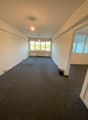 spacious room, carpeted floor, large windows, white walls, 2 wall sockets, ceiling light