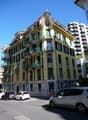 5 story building, yellow exterior, green balconies, multiple windows, stone base