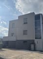 Modern apartment building, glass windows, grey walls, entrance door, small garden
