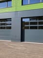 2-story commercial building with green and gray exterior, large windows, and garage doors