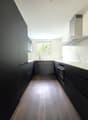 Modern kitchen with black cabinets, white countertops, stainless steel appliances, and a window overlooking the outdoors.