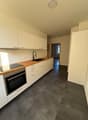 modern kitchen with white cabinets, wooden countertops, black floor, integrated oven, dishwasher, washing machine