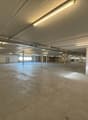 empty large space, industrial setting, white walls, exposed beams, windows, pipes