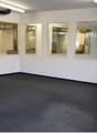 empty room with two entrances, windows, carpet, bright fluorescent lighting