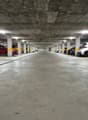 Underground parking garage with concrete ceiling and columns, lined with parked cars on both sides