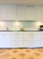 modern, white cabinets, black countertop, stainless steel sink, oven, flowers on countertop, wooden floor