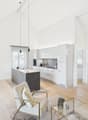 modern kitchen with island, dining table, living room with armchair, coffee table, shelves, wooden floor