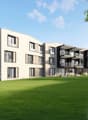 3-story modern apartment building with clean, minimalist design, large windows, and balconies. The building is surrounded by a well-manicured lawn and landscaping.