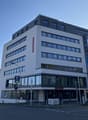 Commercial building, large windows, glass doors, 5 stories, blue sign, flags, banners