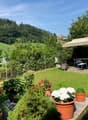 garden with seating area, dining table, canopy, greenery, lawn, and distant hills